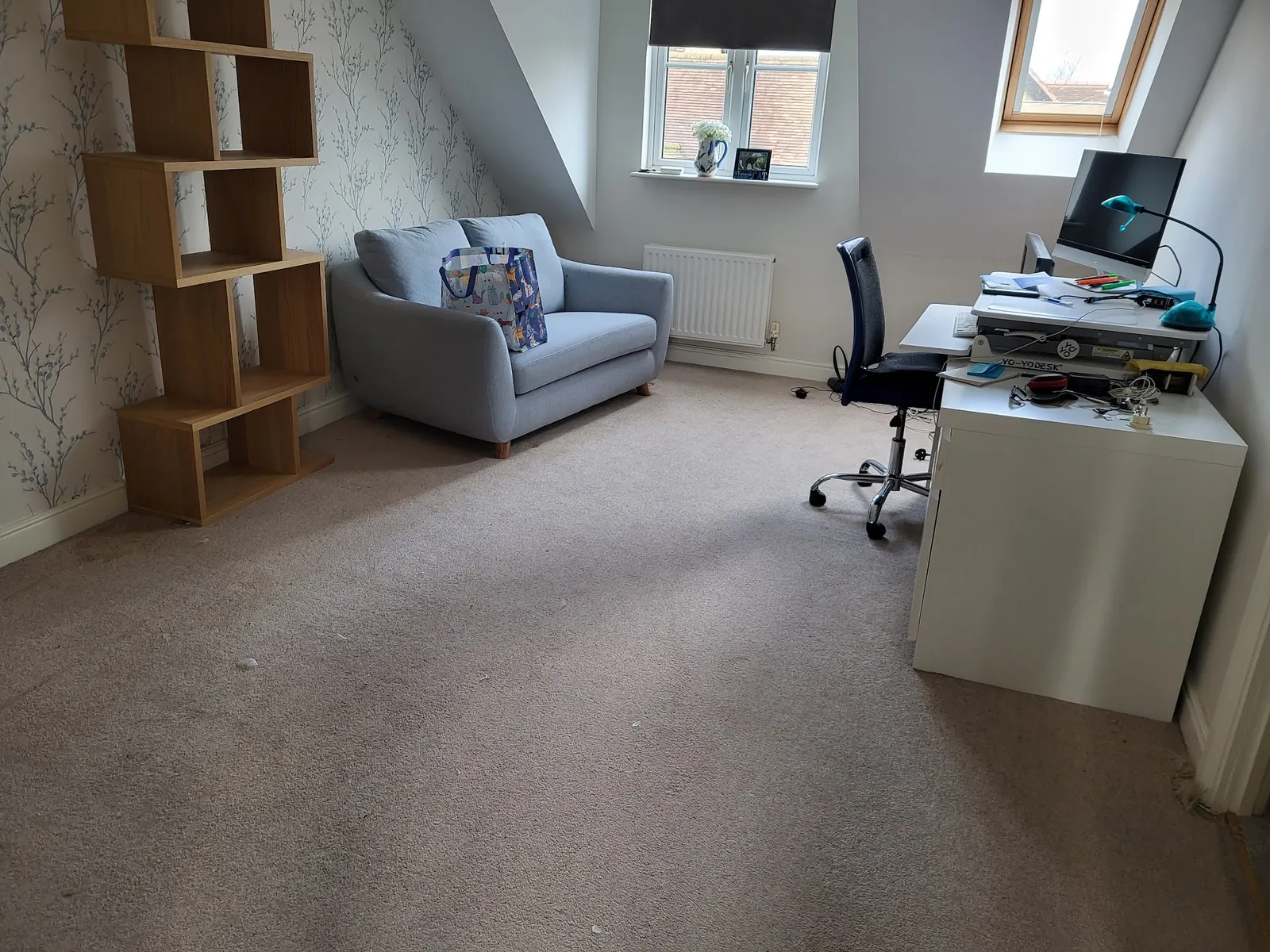 A customer's finished room with light carpet, a sofa and desk