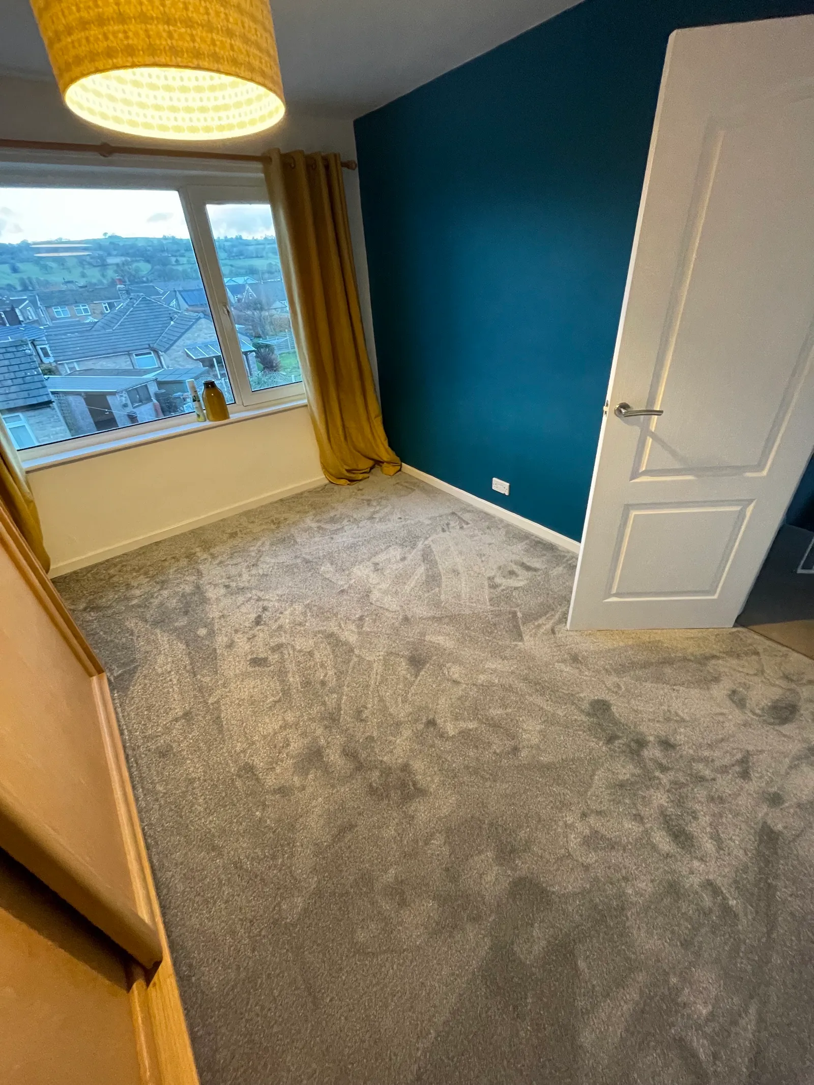 A customer's bedroom with newly fitted carpet, teal wall and yellow curtains